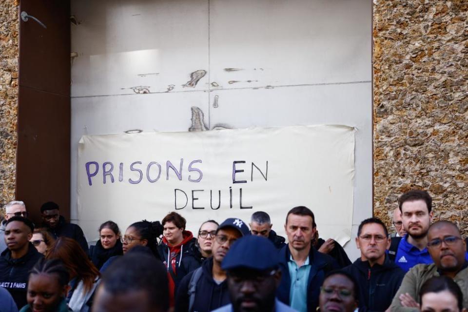 A group of people standing outside La Santé prison with a sign that read 'prisons in mourning'