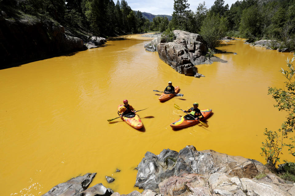 FILE - People kayak in water colored from a mine waste spill at the Animas River near Durango, Colo., on Aug. 6, 2015. Colorado, the U.S. government and a gold mining company have agreed to resolve a longstanding dispute over who’s responsible for cleanup at a Superfund site that was established after a massive 2015 spill of hazardous mine waste. The proposed settlement announced Friday, Jan. 21, 2022, would direct $90 million to cleanup at the Bonita Peak Mining District Superfund site, according to the U.S. Environmental Protection Agency and Denver-based Sunnyside Gold Corp (Jerry McBride/The Durango Herald via AP, File)