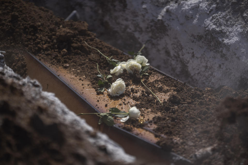 Roses lay atop the coffin containing the remains of Edenir Rezende Bessa, who is suspected to have died of COVID-19, during her burial in Rio de Janeiro, Brazil, Wednesday, April 22, 2020. After visiting 3 primary care health units she was accepted in a hospital that treats new coronavirus cases, where she died on Tuesday. “People need to believe that this is serious, it kills", said her son Rodrigo Bessa who works at a hospital as nurse in the Espirito Santo state. (AP Photo/Leo Correa)