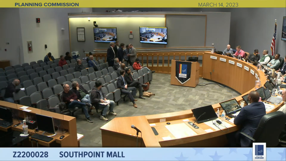 A team representing The Streets at Southpoint speaks in a huddle during a Planning Commission meeting in Durham City Hall on Tuesday, March 14, 2023.