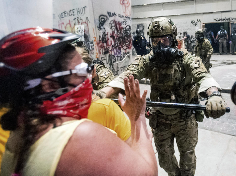 A federal officer pushes back demonstrators at the Mark O. Hatfield United States Courthouse on Tuesday, July 21, 2020, in Portland, Ore. A federal judge is hearing arguments on Oregon's request for a restraining order against federal agents who have been sent to the state's largest city to quell protests that have spiraled into nightly clashes between authorities and demonstrators.(AP Photo/Noah Berger)