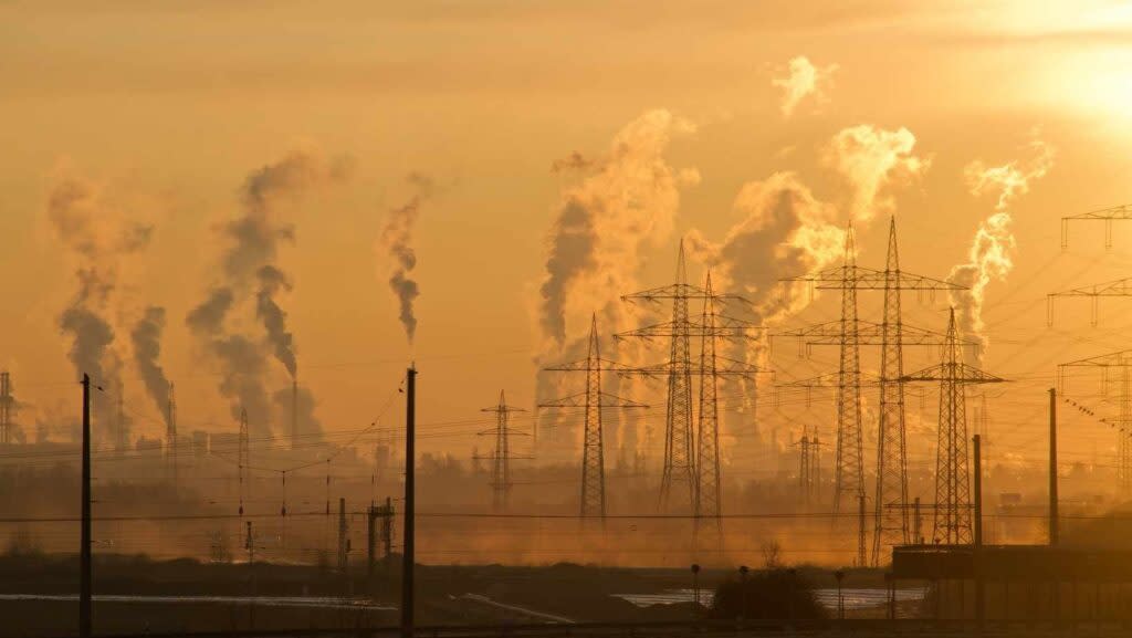 smoke plumes tower over an industrial site at sunrise