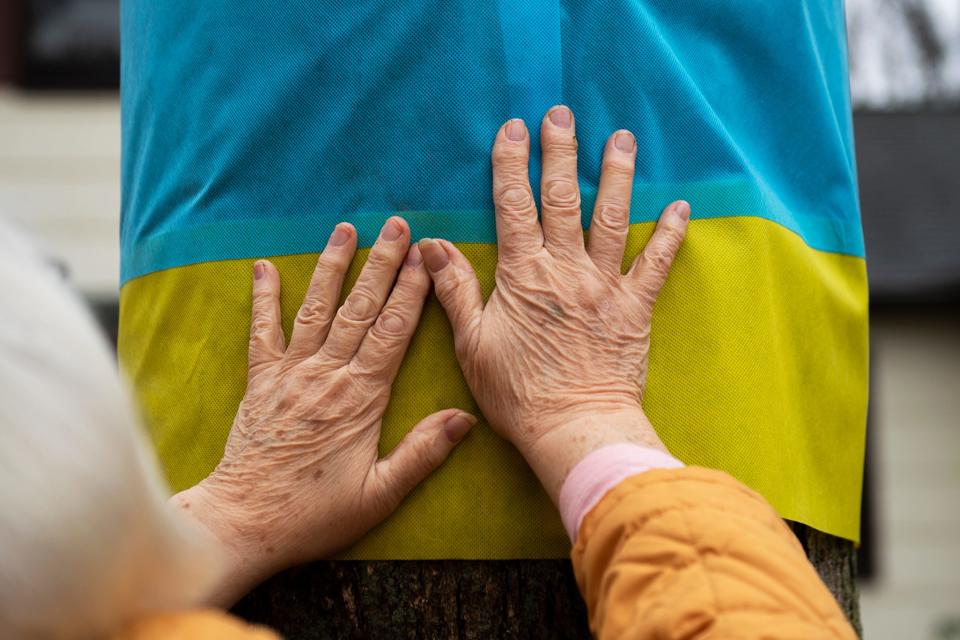 Halyna Lojko wraps a tree with the colors of the Ukrainian flag on Feb. 24 at her home in Morganville.