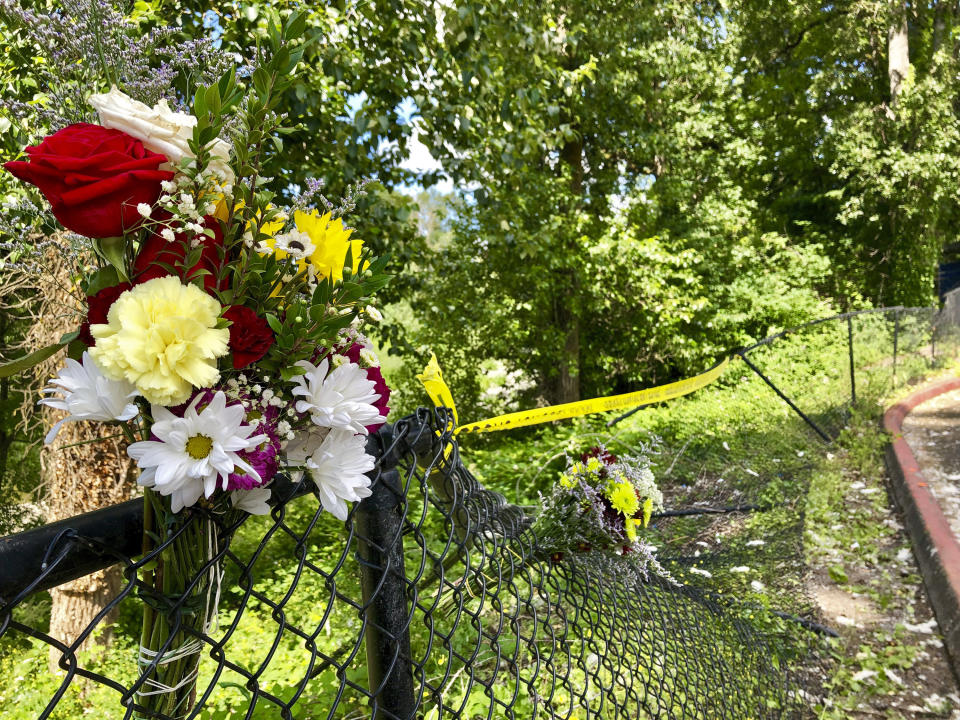 Bouquets of flowers sit on a fence on Wednesday, June 26, 2019, that was knocked down when a driver crashed into a swimming hole in Washougal, Wash., and ran over two German tourists who were sunbathing by the Washougal River, killing them. Police have arrested David Croswell, who lives a few blocks away from the swimming hole, in the deaths of Rudolf Hohstadt, 61, and Regina Hohstadt, 62. (AP Photo/Gillian Flaccus)