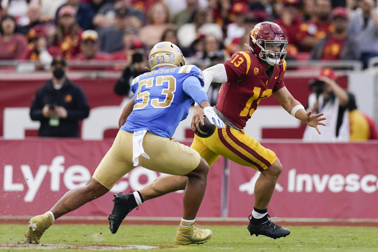 Southern California quarterback Caleb Williams, right, runs as UCLA linebacker Darius Muasau chases during the first half of an NCAA college football game, Saturday, Nov. 18, 2023, in Los Angeles. (AP Photo/Ryan Sun)