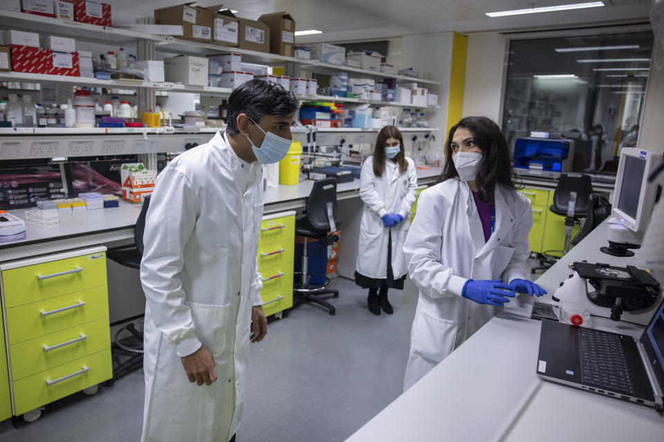 Britian's Chancellor of the Exchequer Rishi Sunak, left, listens during a visit to Imperial Clinic Research Facility at Hammersmith Hospital, where he met staff and was instructed on research techniques, to mark the announcement of his Spending Review, in London, Wednesday, Nov. 25, 2020. (Jack Hill/Pool Photo via AP)