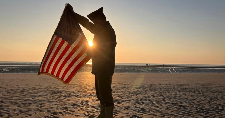 Christophe Receveur, of France, unfurls an American flag he bought six month ago in Gettysburg, Penn., to mark D-Day, Thursday, June 6, 2024 on Utah Beach, Normandy. As the sun sets on the D-Day generation, it's rising again over Normandy beaches where soldiers fought and died exactly 80 years ago, kicking off intense anniversary commemorations Thursday against the backdrop of renewed war in Europe, in Ukraine. (AP Photo/John Leicester)