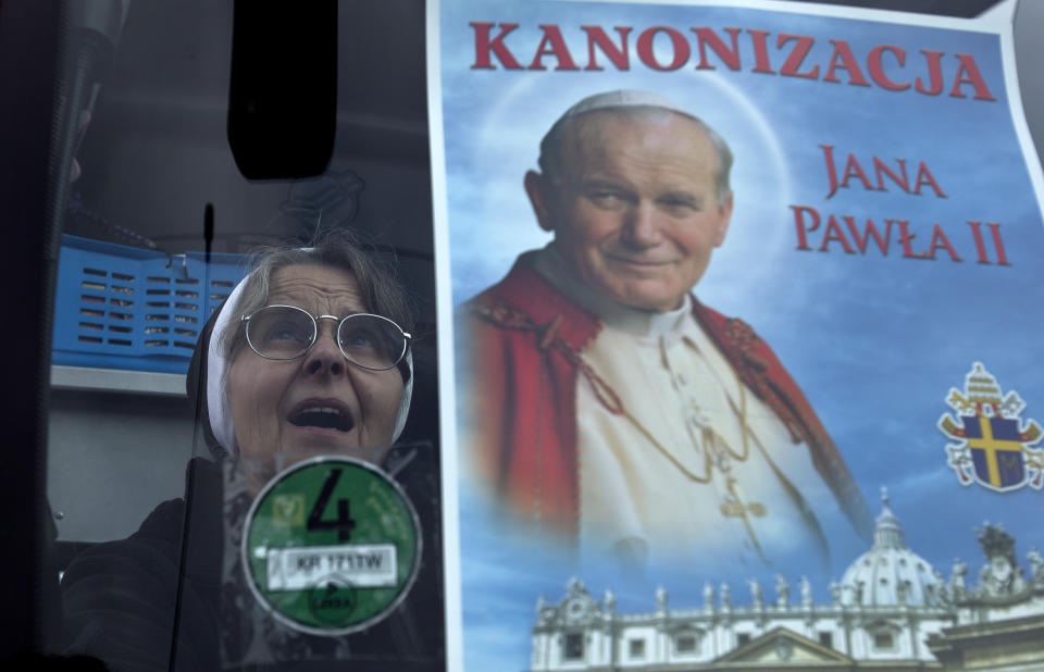 Una monja católica gesticula luego de colocar un cartel del difunto papa Juan Pablo II en el parabrisas de un autobús, en Wadowice, Polonia, el viernes 25 de abril de 2014. Dos autobuses partieron de Wadowice hacia Roma para que peregrinos polacos asistan a la canonización del papa Juan Pablo II el domingo. (Foto AP/Vadim Ghirda)