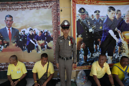 A policeman stands guard as people wait under posters of Thailand's newly crowned King Maha Vajiralongkorn before a coronation procession in Bangkok, Thailand May 5, 2019. REUTERS/Athit Perawongmetha