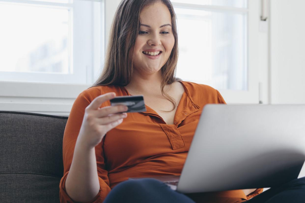 Happy woman ordering something online and paying for it by using her credit card.