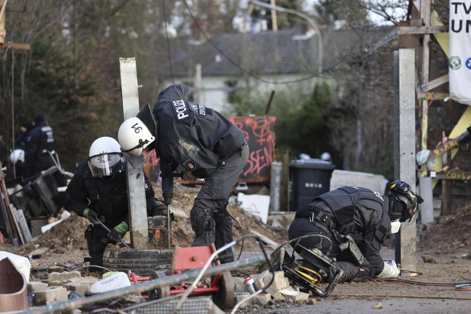 Police officers remove barriers erected by activists at the village Luetzerath near Erkelenz, Germany, Friday, Jan. 13, 2023. Police have entered the condemned village in to evict the climate activists holed up at the site in an effort to prevent its demolition, to make way for the expansion of a coal mine. (Rolf Vennenbernd/dpa via AP)