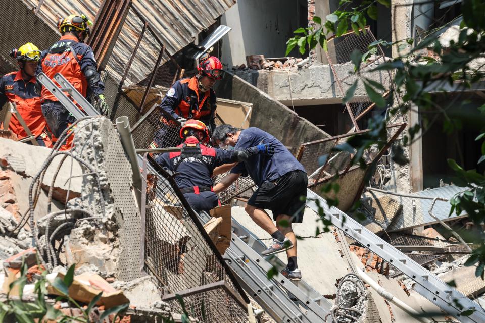 TOPSHOT - This photo taken by Taiwan's Central News Agency (CNA) on April 3, 2024 shows emergency workers assisting a survivor after he was rescued from a damaged building in New Taipei City, after a major earthquake hit Taiwan's east. A major 7.4-magnitude earthquake hit Taiwan's east on the morning of April 3, prompting tsunami warnings for the self-ruled island as well as parts of southern Japan and the Philippines.