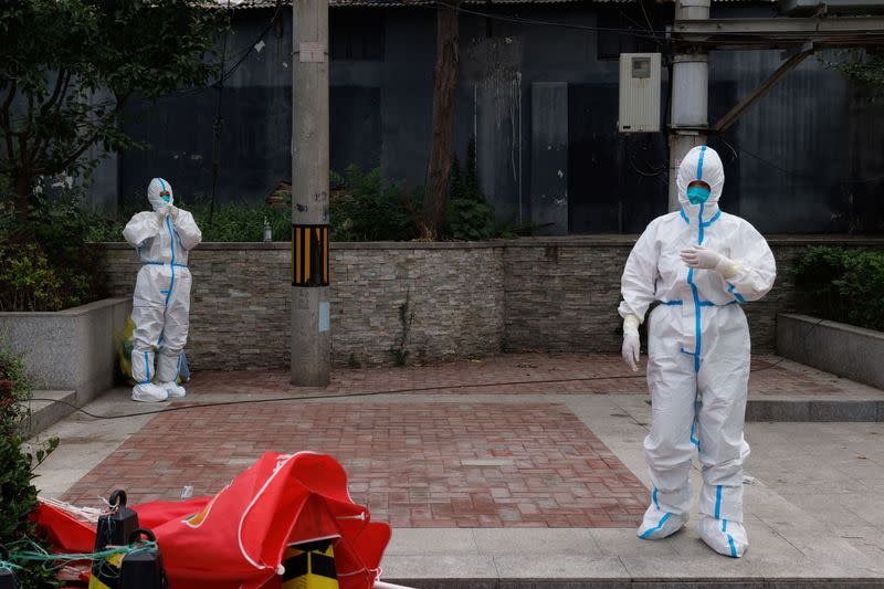 Medical workers in personal protection suits stand at a nucleic acid testing station, following the coronavirus disease (COVID-19) outbreak, in Beijing