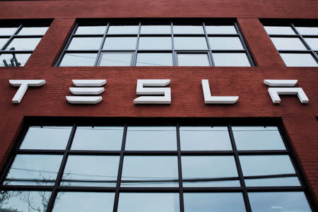 FILE PHOTO: A Tesla logo hangs on a building outside of a Tesla dealership in New York, U.S., April 29, 2016. REUTERS/Lucas Jackson/File Photo