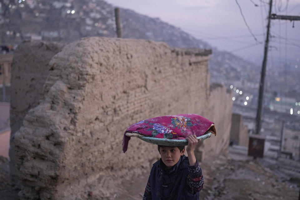 An Afghan boy carries a tray of bread on his head, in Kabul, Afghanistan, Sunday, Dec. 5, 2021. (AP Photo/Petros Giannakouris)