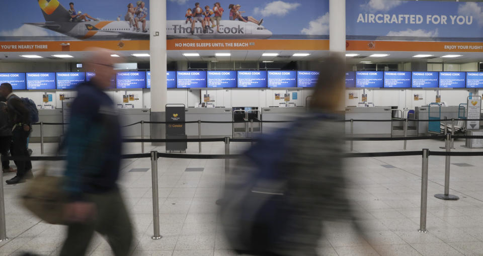 Travelers walk past a section of empty Thomas Cook check-in desks at Gatwick Airport, England, Monday, Sept. 23, 2019. Hundreds of thousands of travelers were stranded across the world Monday after British tour company Thomas Cook collapsed, immediately halting almost all its flights and hotel services and laying off all its employees. (AP Photo/Alastair Grant)