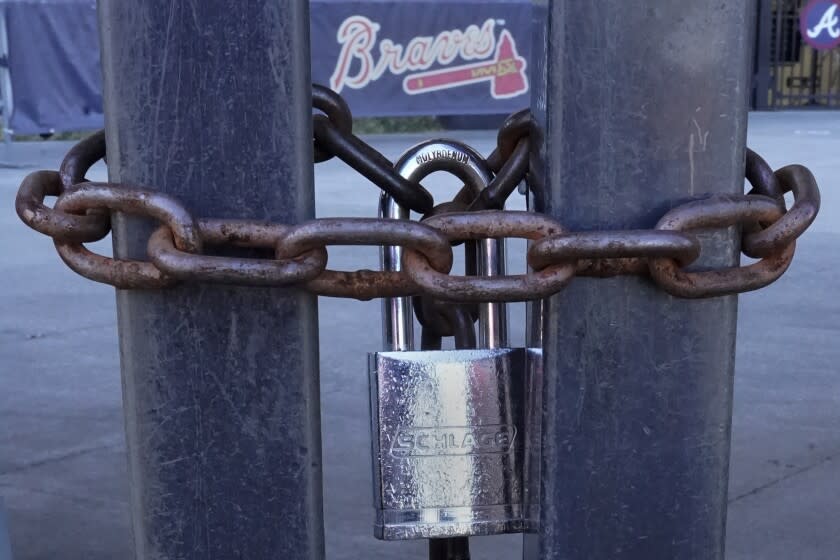 FILE - Locked gates are shown at Truist Park, home of the Atlanta Braves baseball team, Wednesday, March 2, 2022, in Atlanta. Baseball's ninth work stoppage reached 96 days on Monday, March 7, 2022. It is the sport's first labor conflict to cause games to be canceled since the 1994-95 strike wiped out the World Series for the first time in 90 years. (AP Photo/John Bazemore, File)