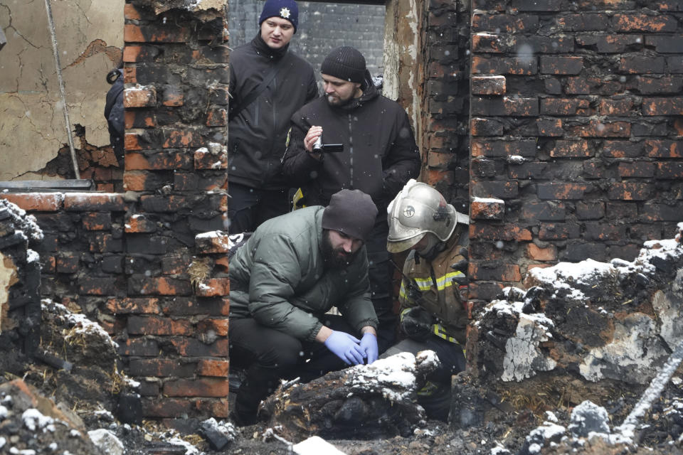 Experts examine a body of a resident killed in a fire as a Russian drone hit his home in a residential neighbourhood, in Kharkiv, Ukraine, Saturday, Feb. 10, 2024. Seven people including three children were killed in the Russian drone attack, said the city administration. (AP Photo/Andrii Marienko)