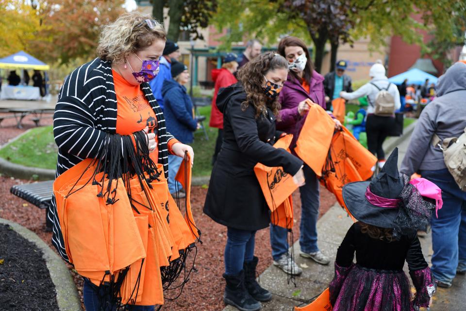 Employees of Hometown Bank pass out treat bags for collecting candy during Main Street Kent’s Family Friendly Halloween in downtown Kent.