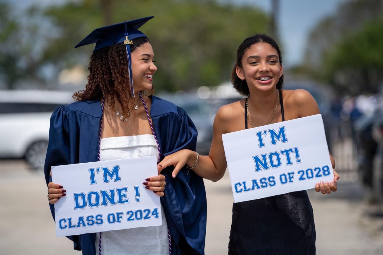 Julia Sampio, left, and her sister Samira Sampio get their photos made by their mom before the Spanish River High School graduation ceremony at the South Florida Fairgrounds on May 13, 2024 in West Palm Beach.