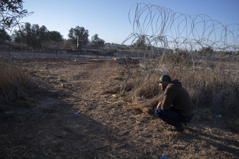 A Palestinian man sits by an opening in a section of Israel's separation barrier, while waiting for the Israeli army to allow him to pass to the other side of the fence, in the West Bank village of Nilin, west of Ramallah, Sunday, Nov. 7, 2021. Nearly two decades after Israel sparked controversy worldwide by building the barrier during a Palestinian uprising, it has become a seemingly permanent feature of the landscape — even as Israel encourages its citizens to settle on both sides. (AP Photo/Nasser Nasser)