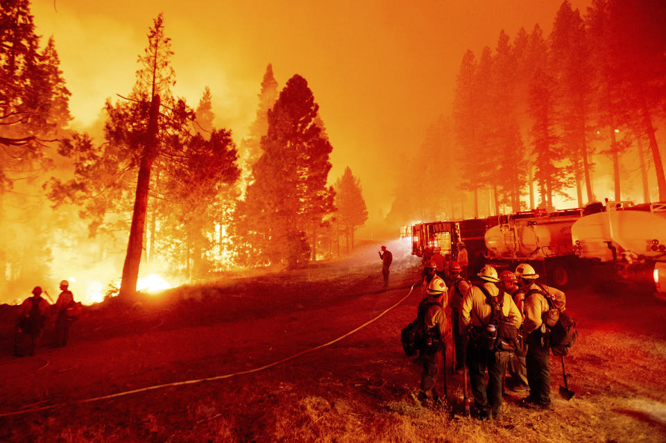 FILE - In this Thursday, Aug. 26, 2021 file photo, the Caldor Fire burns along both sides of Highway 50 as firefighters work to stop its eastward spread in Eldorado National Forest, Calif.. Last week, managers overseeing the fight against the massive wildfire scorching California's Lake Tahoe region thought they could have it contained by the start of this week. Instead, on Monday, Aug. 30, 2021, the Caldor Fire crested the Sierra Nevada, forcing the unprecedented evacuation of all 22,000 residents of South Lake Tahoe. (AP Photo/Noah Berger, File)