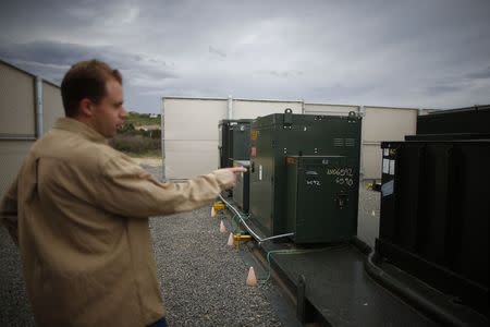 Grant Davis, an engineer at the Energy Storage Group of Advanced Technology, points out a distribution battery energy storage system in Irvine, California January 26, 2015. REUTERS/Lucy Nicholson