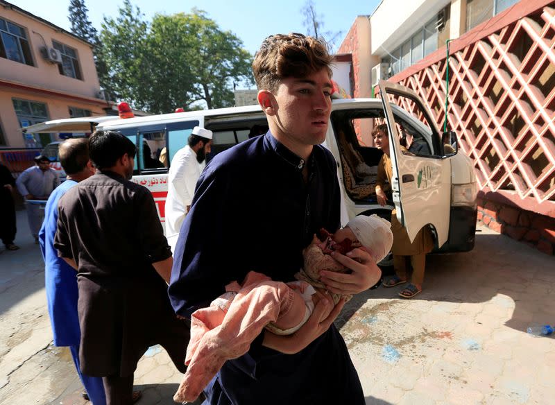 FILE PHOTO: A man carries an injured child at a hospital after a truck bomb blast, in Jalalabad