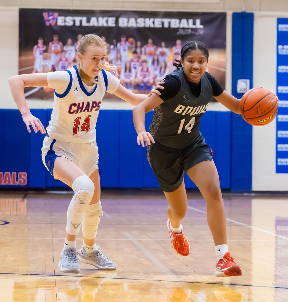 Bowie Bulldogs guard Daniella Williams (14) drives to the basket as Westlake Chaparrals forward Wynn Thorne (14) chases to defend during the second period at the District 26-6A girls basketball game on Tuesday, Jan 2, 2024, at Westlake High School — West Lake Hills, TX.