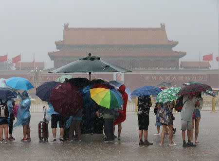 Tourists hold umbrellas as they visit Tiananmen Square during a rainstorm in Beijing, China August 12, 2017. REUTERS/Stringer