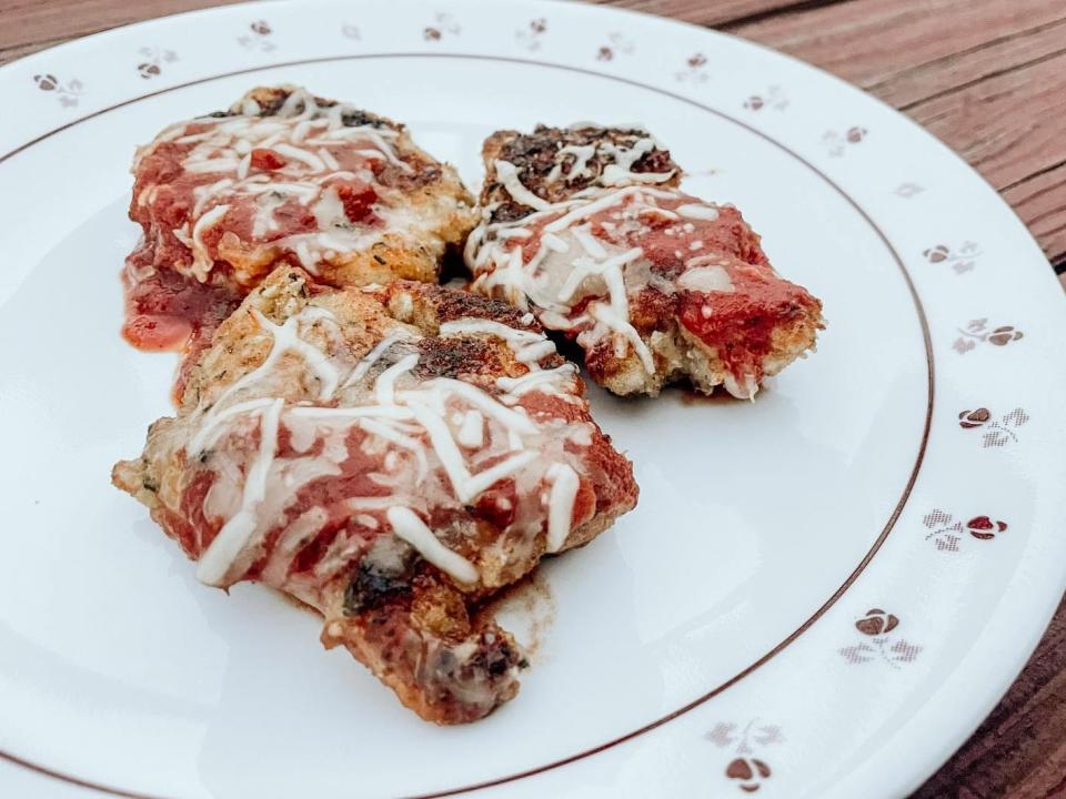 three pieces of chicken parmesan on a white plate