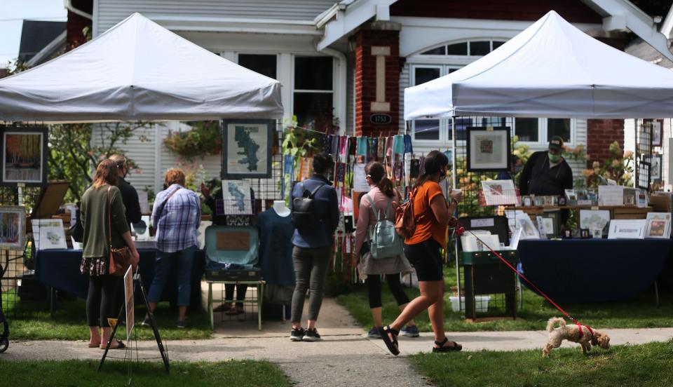 People look at the offerings from local artists on Sept. 13, 2020, at the Washington Heights Front Yard Pop-Up art and music community festival in the 1700-1800 block of North 52nd Street.
