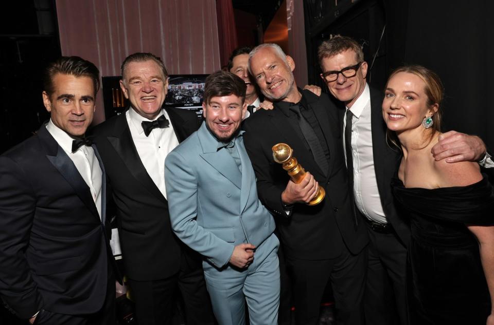 the cast of the banshees of inisherin celebrating backstage with a golden globe statue