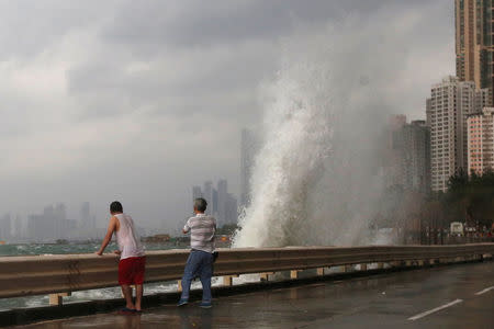People stand beside a big wave on a waterfront as Typhoon Haima approaches in Hong Kong, China, October 21, 2016 . REUTERS/Bobby Yip