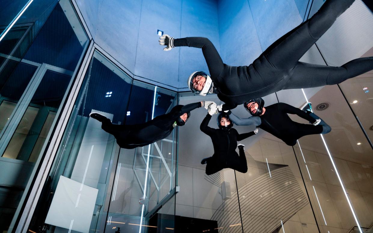 Athletes holding each others hands flying in wind tunnel