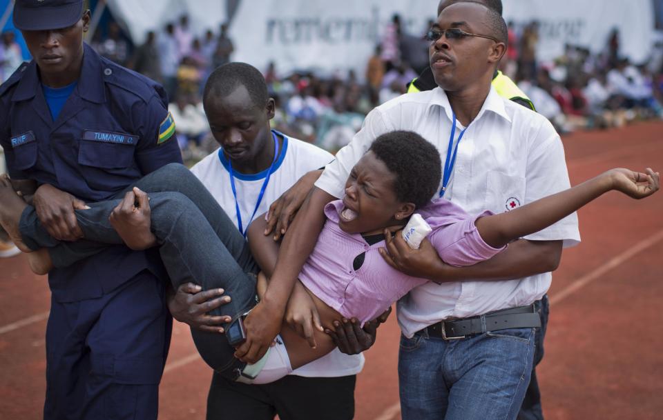 A wailing and distraught Rwandan woman, one of dozens overcome by grief at recalling the horror of the genocide, is carried away to receive help during a public ceremony to mark the 20th anniversary of the Rwandan genocide, at Amahoro stadium in Kigali, Rwanda Monday, April 7, 2014. Sorrowful wails and uncontrollable sobs resounded Monday as thousands of Rwandans packed the country's main sports stadium to mark the 20th anniversary of the beginning of a devastating 100-day genocide. (AP Photo/Ben Curtis)