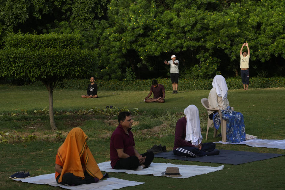 People with their faces covered with scarfs meditate as other perform yoga in a park early morning, in New Delhi, India, Wednesday, June 14, 2023. India's Prime Minister Narendra Modi, known for his reputation of an ascetic, is participating in a yoga session at the U.N. during his three-day visit to the United States. Wednesday's event is aimed to raise awareness worldwide of the benefits of practicing yoga, some nine years after the Hindu nationalist leader successfully lobbied the U.N. to designate June 21 International Yoga Day. Modi has harnessed yoga as a cultural soft power to extend his nation's diplomatic reach and assert his country's rising place in the world.(AP Photo/Manish Swarup)