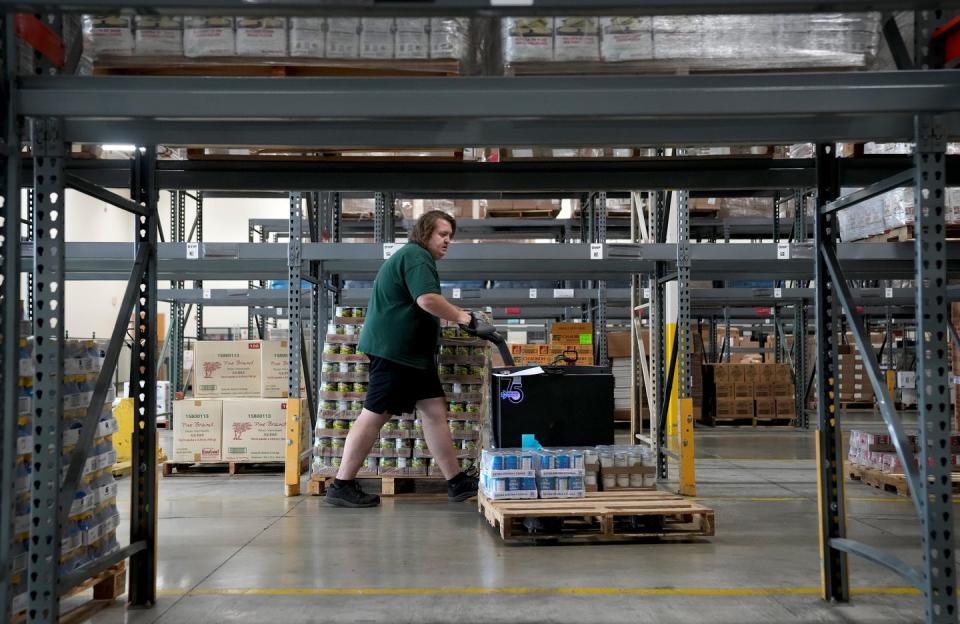Rhode Island Community Food Bank staffer Ben Larkin moves past an empty section of food shelving at the food bank warehouse with products he was collecting for distribution on Monday.