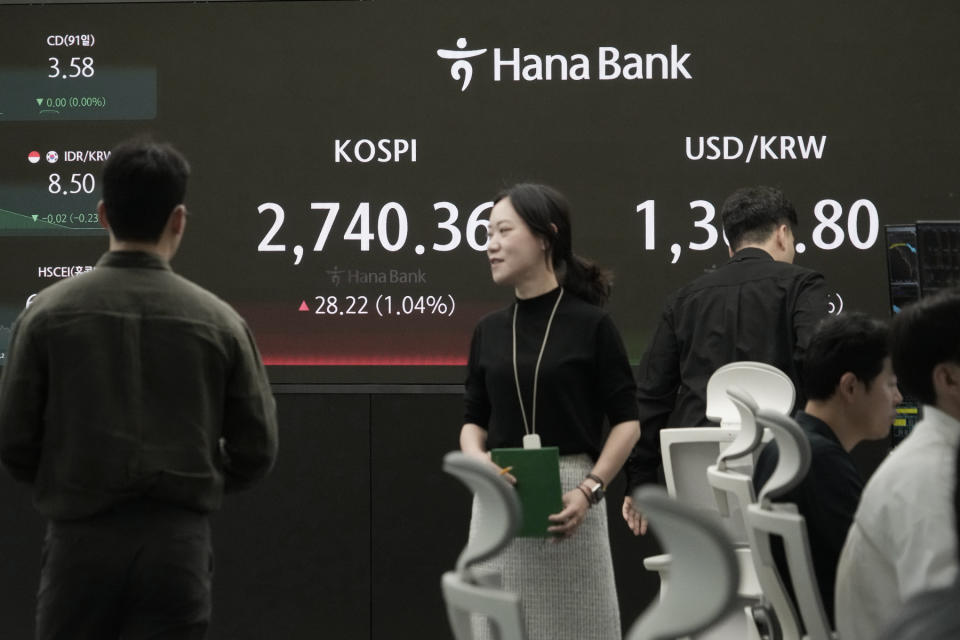 Currency traders pass by the screen showing the Korea Composite Stock Price Index (KOSPI), left, and the foreign exchange rate between U.S. dollar and South Korean won at the foreign exchange dealing room of the KEB Hana Bank headquarters in Seoul, South Korea, Friday, May 10, 2024. (AP Photo/Ahn Young-joon)