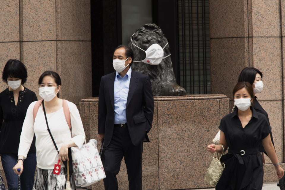 People wearing face masks walk across a traffic intersection, passing by a statue of a lion with a face mask displayed at a department store in the famed Ginza shopping neighborhood in Tokyo on Friday, May 21, 2021. Japan has approved the use of two new vaccines - Moderna and AstraZeneca - hours ahead of an expansion of a state of coronavirus emergency that will cover roughly 40% of the population. It’s the latest effort to contain a worrying surge in infections nine weeks ahead of the opening of the Tokyo Olympics.(AP Photo/Hiro Komae)