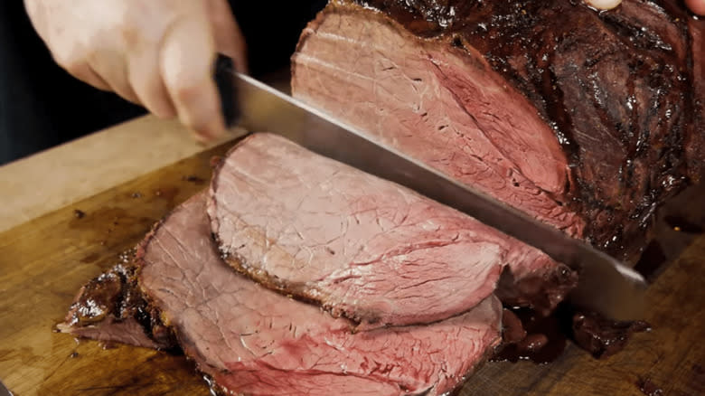 Hands slicing a beef knuckle roast