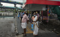 People wearing face masks to protect from the new coronavirus as they wait for bus transport in Kochi, Kerala state, India, Monday, June 1, 2020. More states opened up and crowds of commuters trickled on the roads in many cities as India's three-phase plan to lift the virus lockdown kick started Monday amidst an upward trend in new infections and fatalities due to COVID-19. (AP Photo/ R S Iyer)