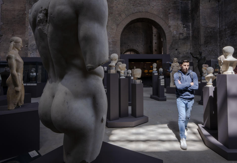 A journalist walks amid statues of the exhibition 'Between us and the ancients. The instant and eternity' in Rome's Diocletian Baths, Wednesday, May 3, 2023. The exhibition will open to the public from May 4 through July 30, 2023. (AP Photo/Domenico Stinellis)