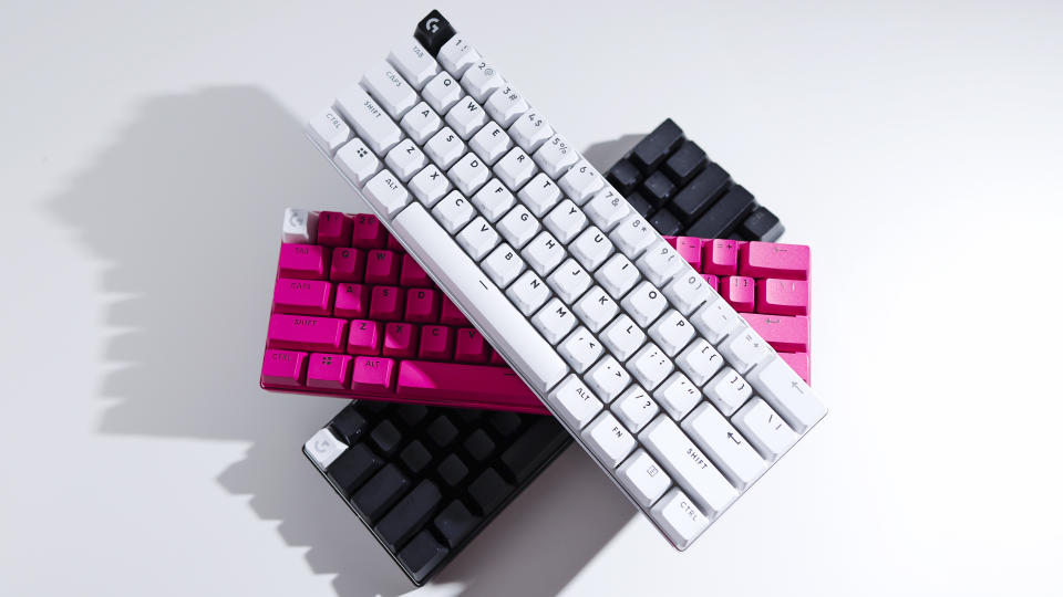 Tres teclados Logitech G Pro X 60, uno blanco, uno rosa y otro negro, están apilados uno encima del otro sobre un fondo blanco.