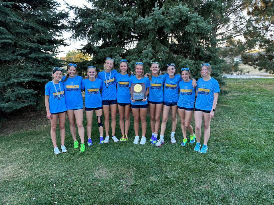 The Timnath girls cross country team poses for a photo with the championship trophy after winning the Colorado Class 3A region 4 team title at Monfort Park in Greeley on Thursday, Oct. 19, 2023.