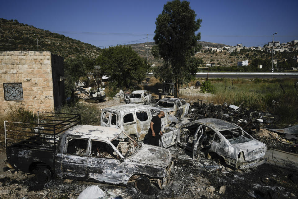 A Palestinian man inspects scorched cars, including some junked for spare parts, in the West Bank village of A Laban al-Sharkiyeh, Wednesday, June 21, 2023. Israeli settlers set fire to cars after four Israelis were killed by Palestinian gunmen in the northern West Bank on Tuesday. (AP Photo/Majdi Mohammed)