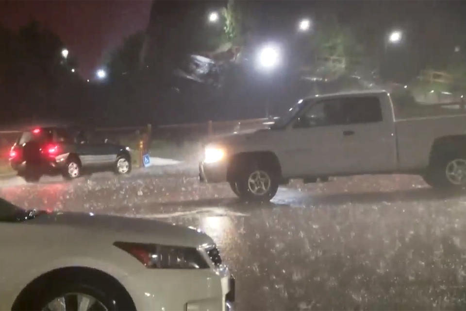 In this image taken from video, hail fails on vehicles during a storm at the Red Rocks Ampitheatre, Wednesday evening, June 21, 2023, in Morrison, Colo. Seven people were hospitalized, according to KMGH-TV. None of those taken to hospitals had life-threatening injuries, and up to 90 people were treated for injuries at the amphitheater, according to West Metro Fire Rescue. (Denver7 via AP)