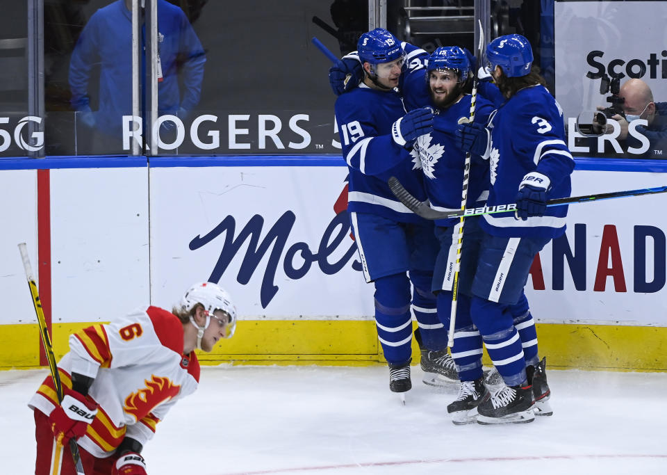 Toronto Maple Leafs forward Jason Spezza (19) celebrates his goal with teammates Alexander Kerfoot (15) and Justin Holl (3) as Calgary Flames defenseman Juuso Valimaki (6) looks on during first-period NHL hockey game action in Toronto, Saturday, March 20, 2021. (Nathan Denette/The Canadian Press via AP)