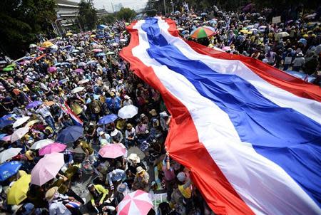 Anti-government protesters unveil a large Thai flag as they descend on Government House in Bangkok December 9, 2013. REUTERS/Dylan Martinez