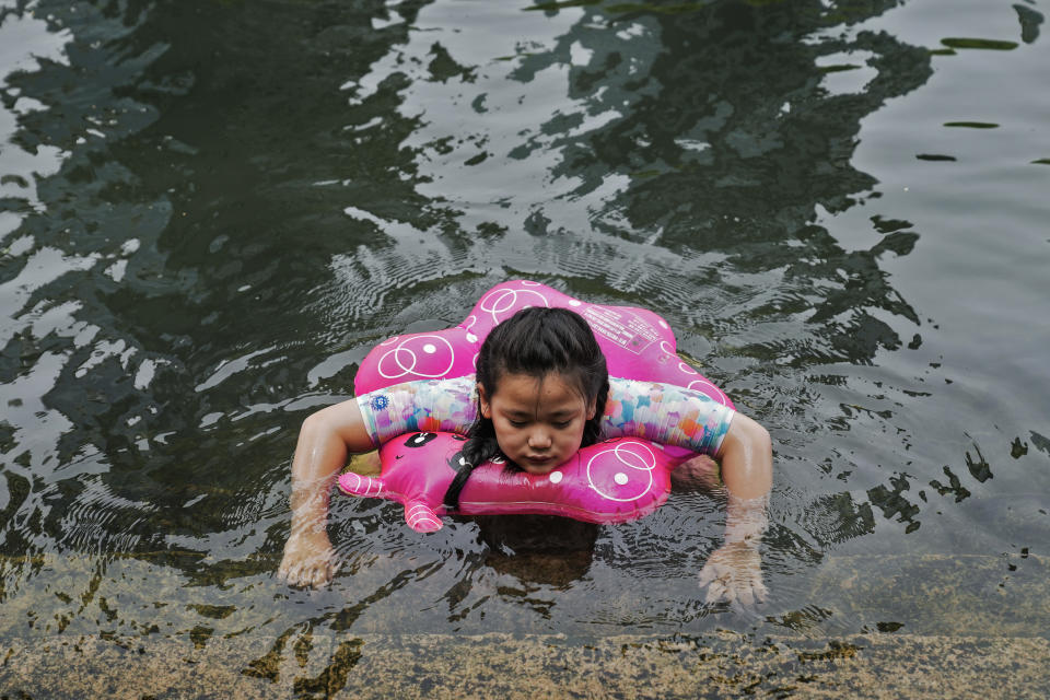 A girl cools herself at an urban waterway on a hot day in Beijing, Monday, July 3, 2023. Heavy flooding has displaced thousands of people around China as the capital had a brief respite from sweltering heat. Beijing reported 9.8 straight days when the temperature exceeded 35 C (95 F), the National Climate Center said Monday. (AP Photo/Andy Wong)